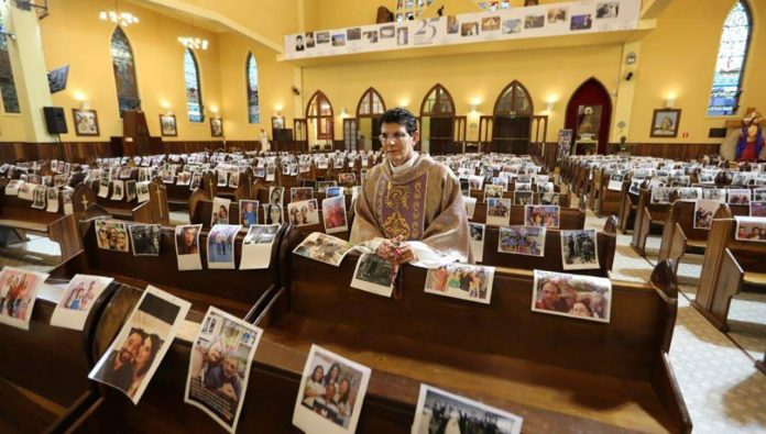 Ao invés de lotar igrejas e prometer cura, Padre reza missa com foto dos fiéis nos bancos