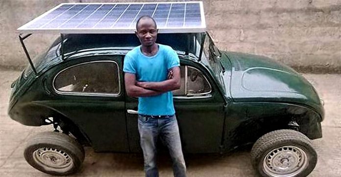 Estudante nigeriano transforma Fusca em um carro movido a energia solar. Ele sorri de orgulho.