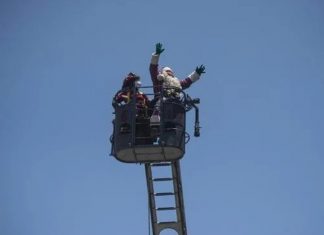 Papai Noel usa escada dos bombeiros para levar presentes a crianças com Covid no Peru